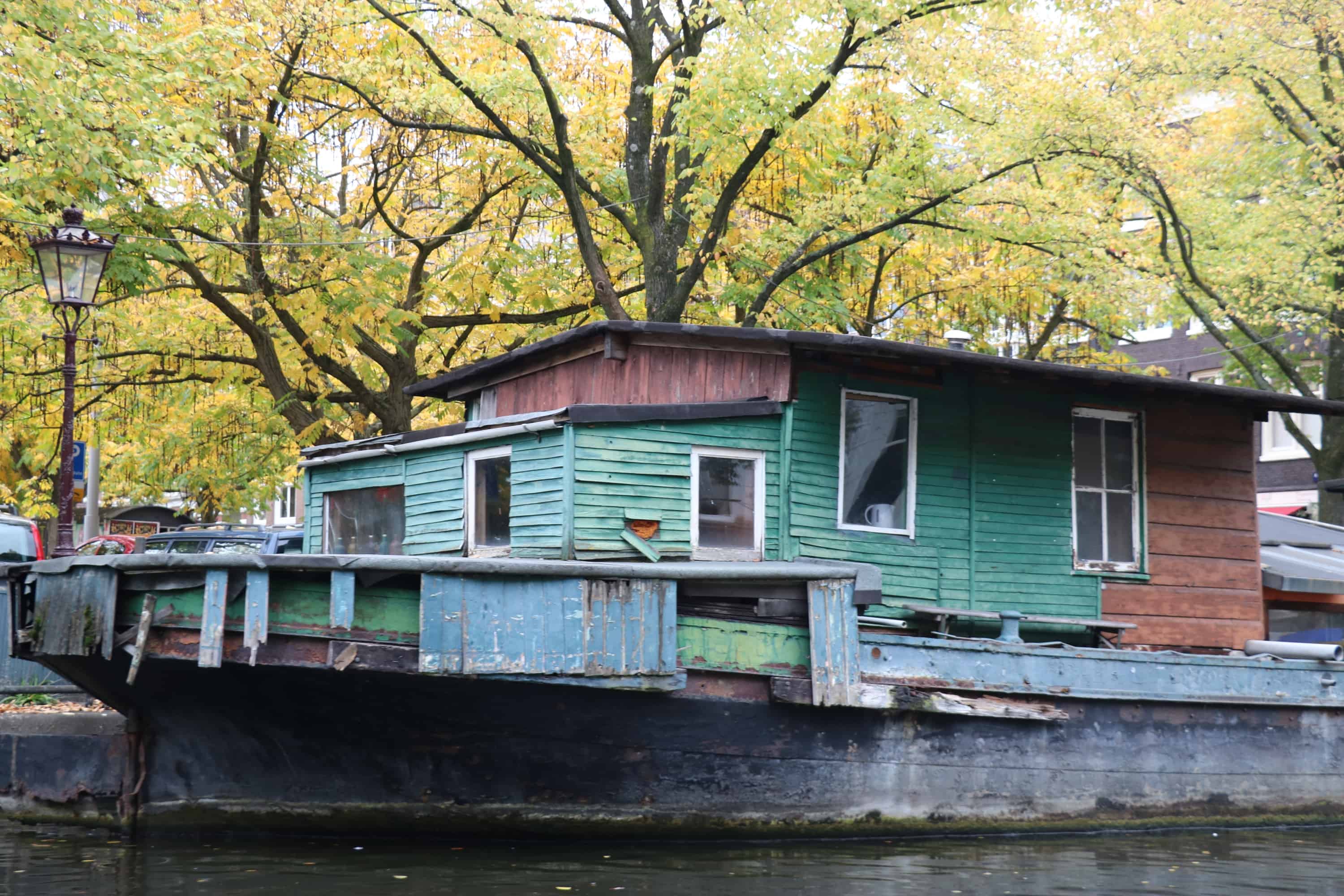 A run down houseboat with peeling paint floats in an Amsterdam canal