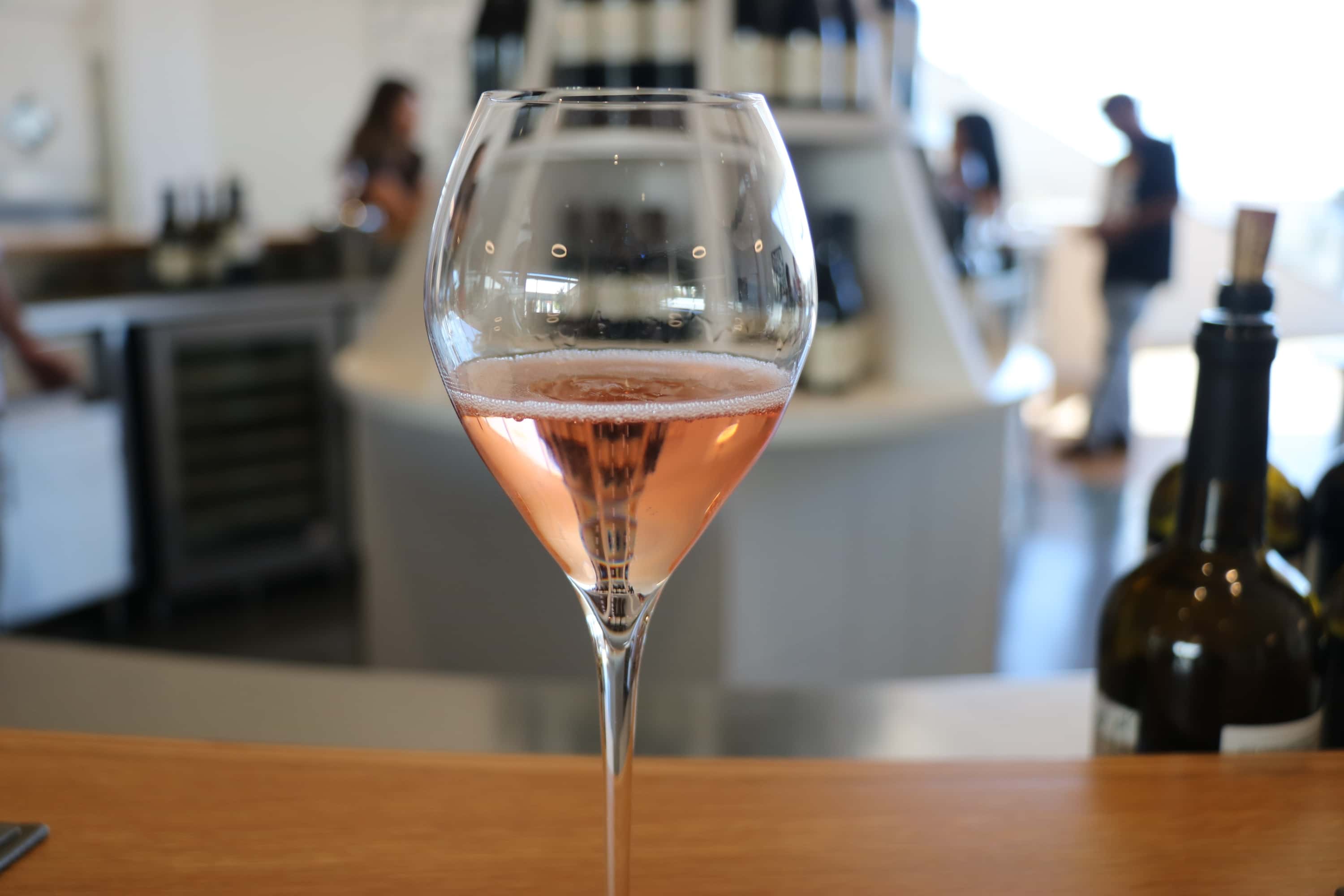 A glass of rose wine on a wooden bench