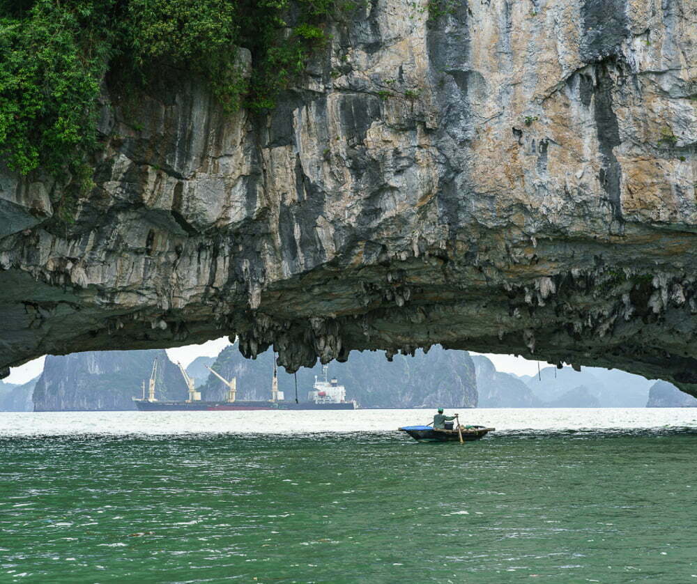 A kayak paddling under a wall of stone on Halong Bay