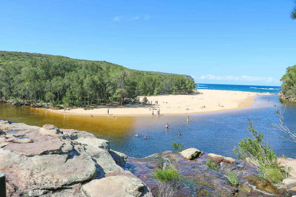 A lagoon running into the sea with people swimming