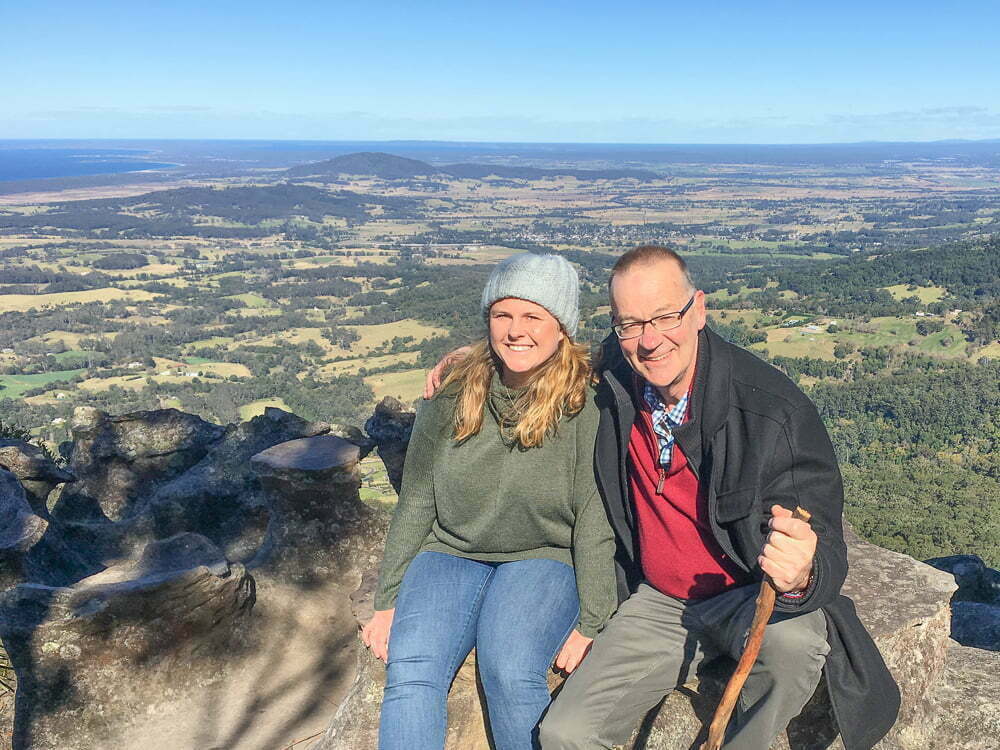 A woman and a man sitting at the top of a mountain