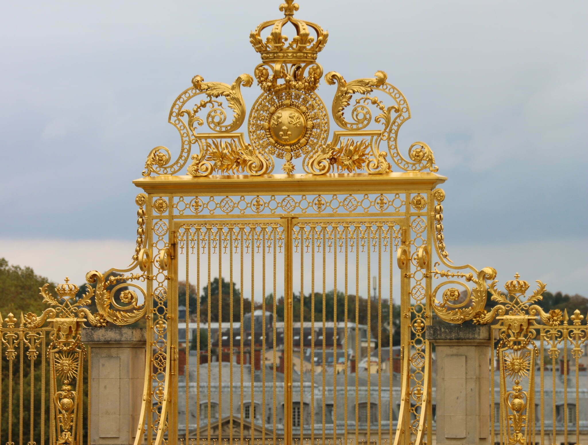 A gilded, golden gate with a crown and sun at the top of the gate