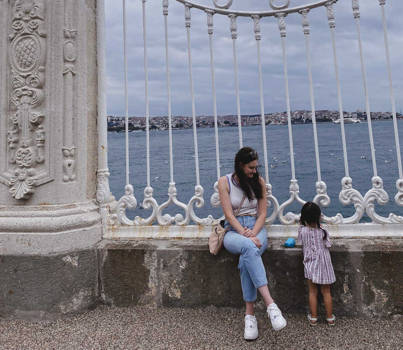 Is Istanbul stroller friendly? Amanda and her daughter sit on a fence with the sea behind them